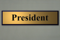 A gold sign that says "President" hangs on a wall.