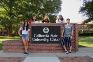 Five students pose next to the California State University Chico sign on a sunny day