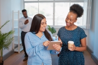 Two businesswomen talk in the office with digital tablet