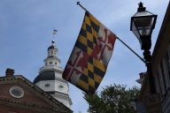 The Maryland state flag flies next to the state Capitol building and a lamppost