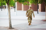 A military service member in fatigues on a college campus