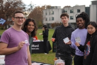 A group of Bard students stand holding voting buttons and cards about the 26th Amendment.