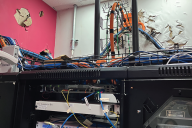 An image from the report of a college’s server room with wires everywhere and paint damage from Hurricane Maria. 
