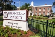 A sign reads “Bethune-Cookman University” in large maroon letters in front of a campus building.