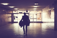 Silhouette of a man in a suit walking through an empty hallway at night.