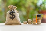 Bag of money and coins lined up behind a graduation cap