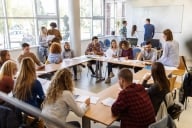 Large group of young students talking among themselves while studying in the classroom