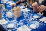 A table set for Passover dinner with blue plates and tablecloths and matzah in the center.