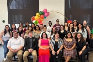 A group of students wearing dressy casual clothing smile for a photo 