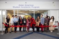 Staff, faculty and students pose in front of the Asian American Student Academic Program office for its ribbon cutting