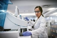 A female scientist wearing protective clothing and eyewear while working in a lab