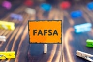 An orange sign with the word FAFSA in bold blacl letters. 
