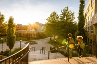 Rear view of two university students walking down campus stairs at sunset