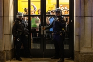 Police outside glass doors of a building at Columbia, with a throng of student protesters visible inside.