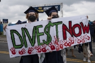 George Washington University graduates holding a sign with the words “Dive$t Now.”