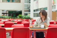 A student sits alone in a dining facility