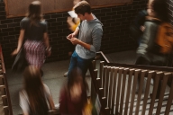 Young man focusing on his phone while other students pass by