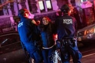 Two New York Police Department officers arresting a female protester, her face anguished.