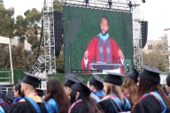 John Legend is pictured on the big screen in graduation regalia as he speaks to Loyola Marymount University students.
