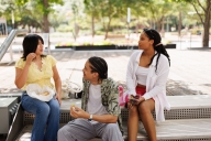 Three college students sit outside eating food