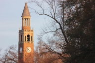 The tall, skinny bell tower can be seen against a backdrop of blue sky and surrounding bare trees in this stock photo of the University of North Carolina at Chapel Hill campus.
