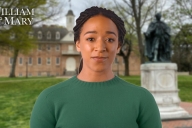 An AI image of a woman with brown skin and black hair, wearing a green top, standing in front of the Wren Building at the College of William & Mary