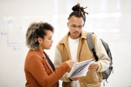 Professor explaining topics to student who is holding a notebook 