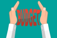 An illustration of two hands squeezing the word "budget."
