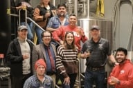 Staff from Western Oregon University and Xicha Brewing pose for a photo holding draft beers