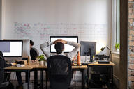 Young professional sits stressed working at a desk.