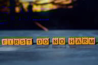 The words "First do no harm," spelled out in wooden blocks.