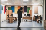 Lone person in silhouette standing in front of glass-windowed office