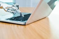 Robot's hand typing on keyboard.