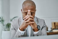 A man leans his head against his hands in an office. 