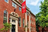 A flag with the Harvard University logo hangs above the entrance of Harvard's Lehman Hall. 