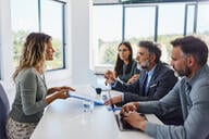 A female job candidate sits across from a group of three people in a job interview. 