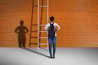 A student stands in front of a ladder with a couple of missing rungs.