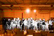 A group of people on crowded stage without an audience.