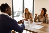A photo of a job candidate meeting with two interviewers; they are engaged in an animated discussion.