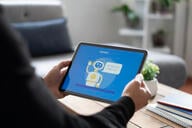 A close-up of a man holding a tablet with a chat bot open on the screen.