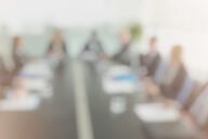 A blurry, out-of-focus picture of a group of trustees around a board table. 