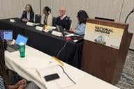 Four panelists sit at a table next to a lectern with the Education Writers Association logo on it.
