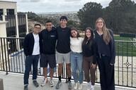 Six students smile together outside on a balcony at the University of San Diego.