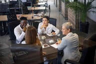 A group of four professionals sits around a conference table discussing ideas. 