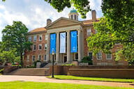 The South Building at the University of North Carolina at Chapel Hill is adorned with banners on a beautiful spring day.