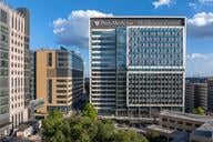 Rendering of the exterior of the Penn Medicine glass and steel Middleman Center against a blue sky with trees in front.