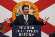 Florida governor Ron DeSantis standing in front of a Florida flag and behind a podium with a sign that says "Higher education reform"