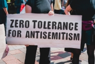 A person holds a sign saying "Zero tolerance for antisemitism"