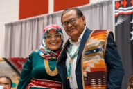 Navajo Technical University president Elmer Guy and Wafa Hozien, university academic administrator, stand together smiling at a campus event celebrating the new Ph.D. program. Both are wearing colorful Native prints. 