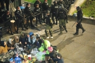 A photo showing many police officers standing in a line near a circle of protesters.